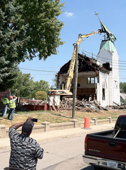 Denny Excavating workers use a large excavator to remove the Holy Angels Church steeple on Aug. 22 during demolition of the 109-year-old frame church, which was badly deteriorated. It was condemned by city inspectors last year. The church was located at the corner of West 28th Street and Dr. Martin Luther King Jr. Street in Indianapolis. Land for the parish was purchased in 1899 by Father Stephen Donoghue, assistant pastor of St. John the Evangelist Parish in Indianapolis. The cornerstone was laid on April 26, 1903, and the church was dedicated on Oct. 4, 1903. (Submitted photo by Eric Atkins)