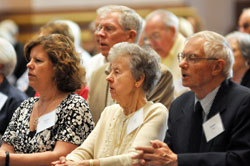 Andra Leipa of St. Monica Parish in Indianapolis, left, and her parents, Vija and Leons Leipa of St. Malachy Parish in Brownsburg, kneel during a Mass for Miter Society members at SS. Peter and Paul Cathedral in Indianapolis on May 7. (Photo by Natalie Hoefer)	