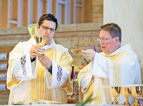 Deacon Anthony Armbruster, left, elevates a chalice at a Mass on April 30, 2023, at Our Lady of Perpetual Help Church in New Albany. Celebrating the Mass is Father Joseph Feltz, right, the parish’s pastor. (Photo courtesy of Saint Meinrad Archabbey)