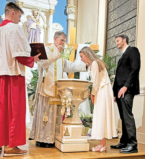 Father Jonathan Meyer baptizes Ashley Akins during the Easter Vigil Mass on March 31 in St. Martin Church of All Saints Parish in Dearborn County. Pictured at right is her sponsor Kyle Gutfreund. At left is altar server Luke Klare. (Submitted photo)