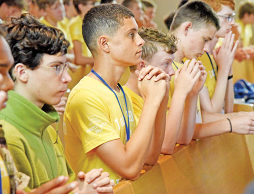 Participants in Bishop Bruté Days kneel in prayer on July 8 in St. Paul Church in New Alsace, a campus of All Saints Parish in Dearborn County, during Bishop Bruté Days, the archdiocese’s annual vocations camp. They are, from left, Sebastian Alvarez, Aidan McKay, Joshua Fuller, Patrick Taber and Jacob Branaham. (Photo by Sean Gallagher)